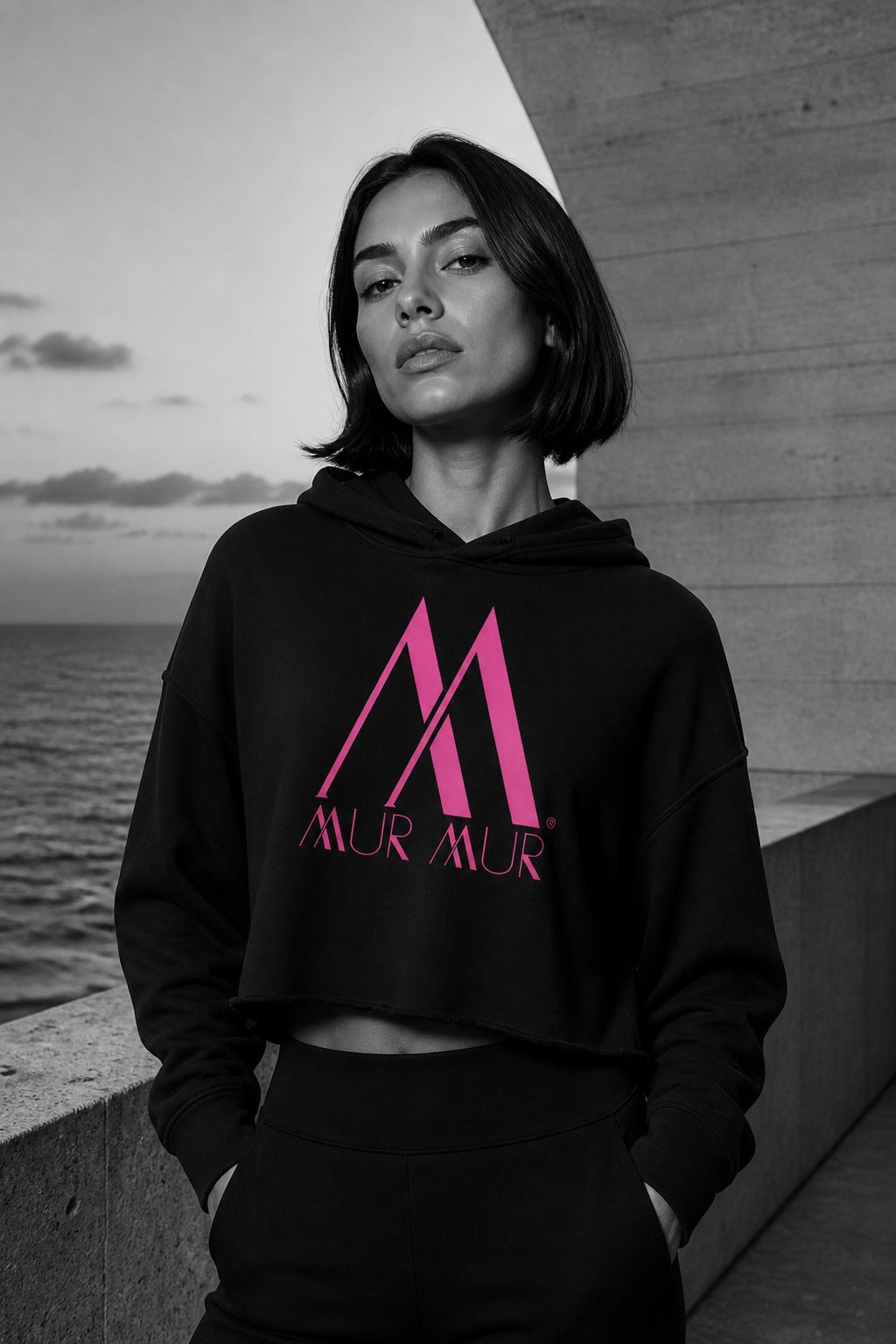 Woman wearing the black Mur Mur raw-hem crop hoodie with pink logo