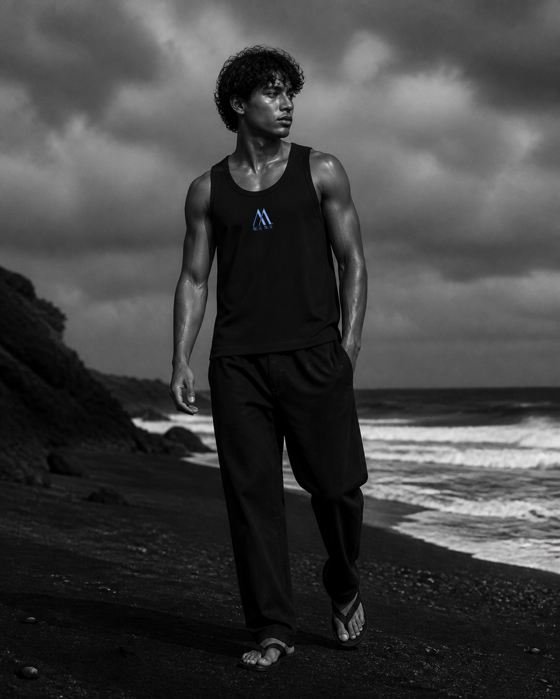 Model wearing the Mur Mur performance tank on a black-sand coast