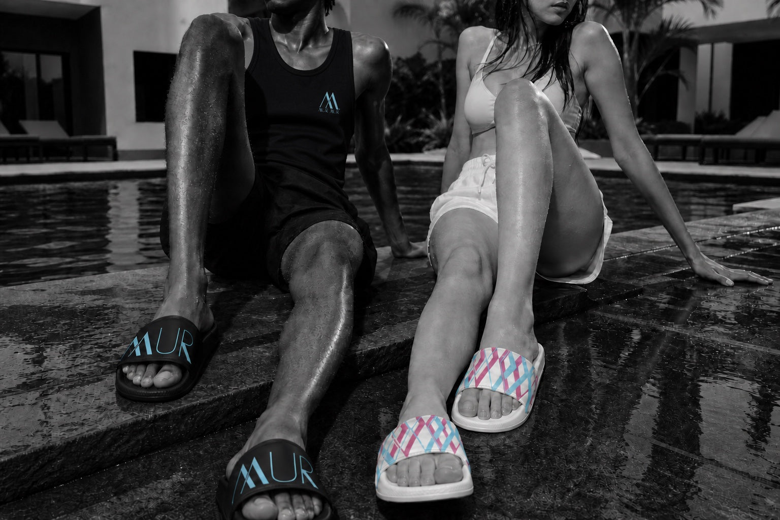 Two models wearing live Mur Mur black and white slide colorways at the pool